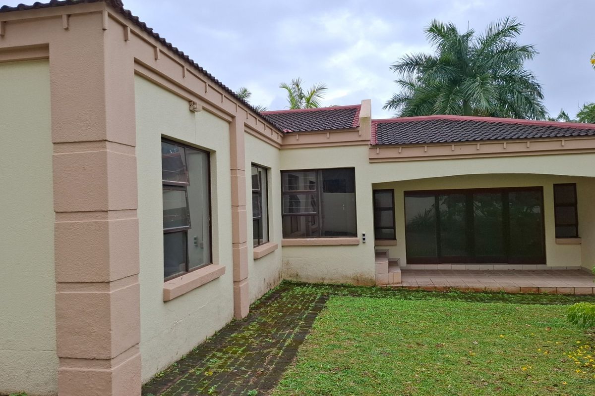 Rear exterior view of the townhouse featuring a paved patio area, sliding glass doors, and a small garden space.