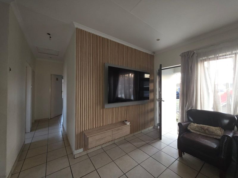 Living room featuring a modern slatted wood accent wall, floating media console, and tiled flooring, with direct access to the exterior.