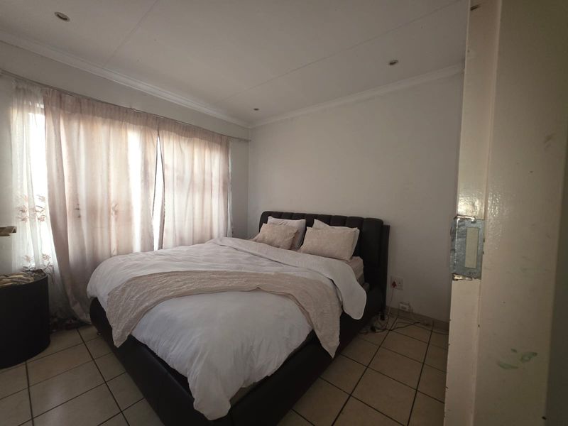 A standard bedroom featuring tiled flooring and recessed downlighting, offering a neutral base for personalization.