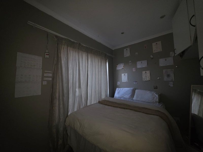 A compact bedroom featuring recessed downlighting, built-in cabinetry, and a window dressed with curtains.