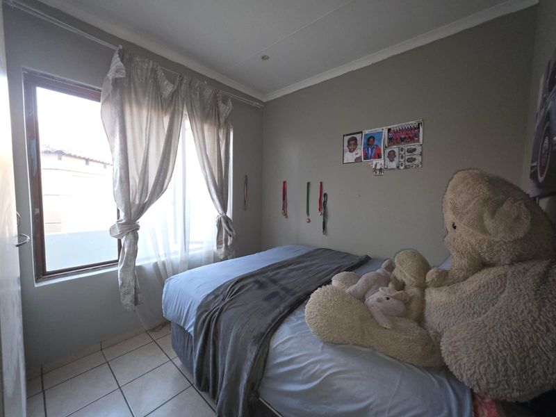 A bedroom featuring tiled flooring, recessed ceiling lighting, and a window allowing natural light.