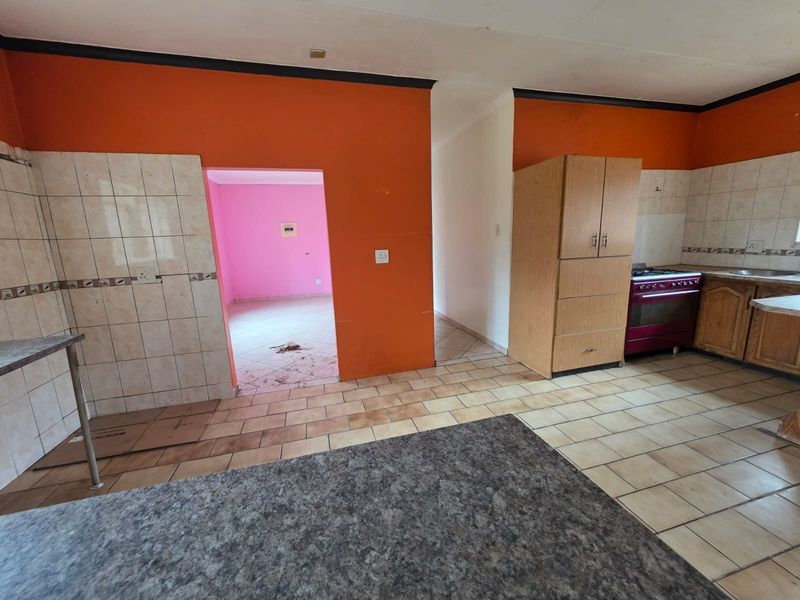 A dated kitchen area featuring tiled flooring, built-in cabinetry, and a tiled backsplash, requiring cosmetic updates to modernize the space.