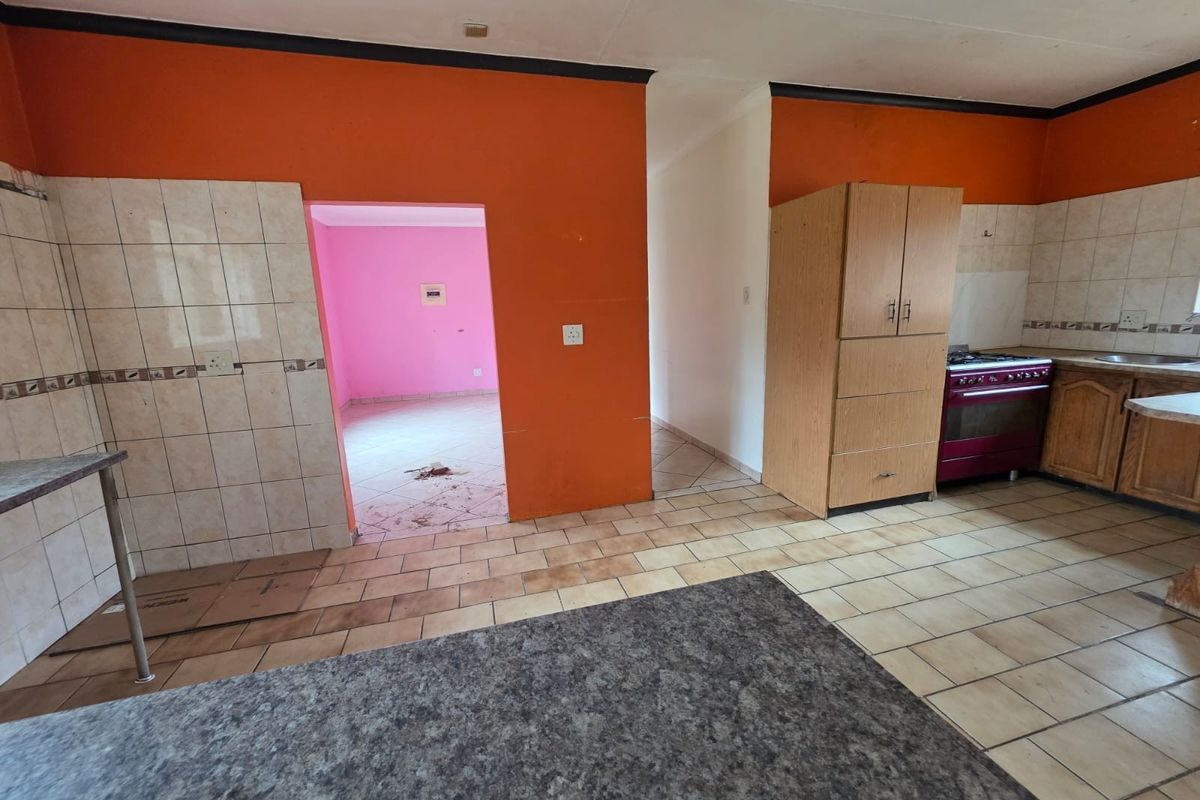 A dated kitchen area featuring tiled flooring, built-in cabinetry, and a tiled backsplash, requiring cosmetic updates to modernize the space.