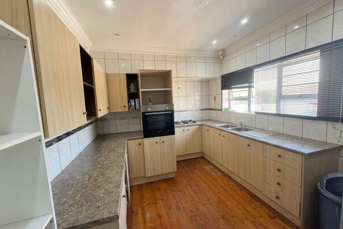 A functional kitchen featuring light wood cabinetry, laminate countertops, built-in oven, gas hob, and timber flooring, offering a practical layout for daily use.