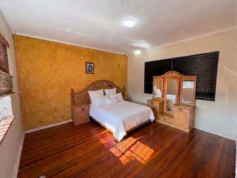 A bedroom featuring hardwood flooring, a textured accent wall, and a recessed ceiling light, providing a functional space with potential for modern updates.