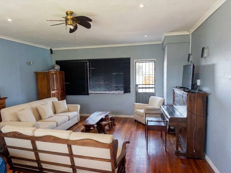 A spacious living room featuring polished hardwood flooring, a ceiling fan, and recessed lighting, with direct access to an exterior security door.