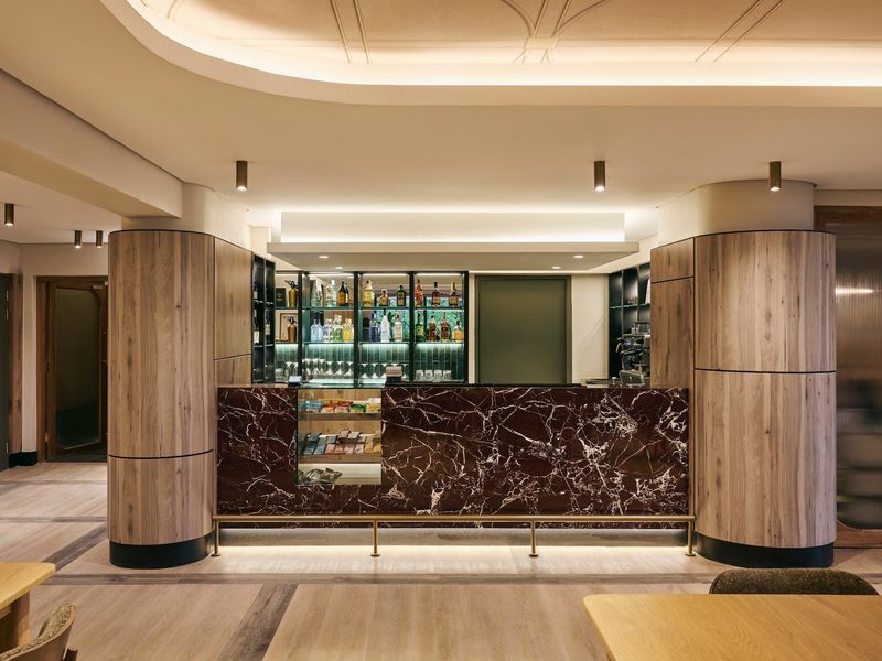 A sophisticated, modern bar area featuring a striking dark marble counter, custom wood paneling, and elegant integrated lighting.