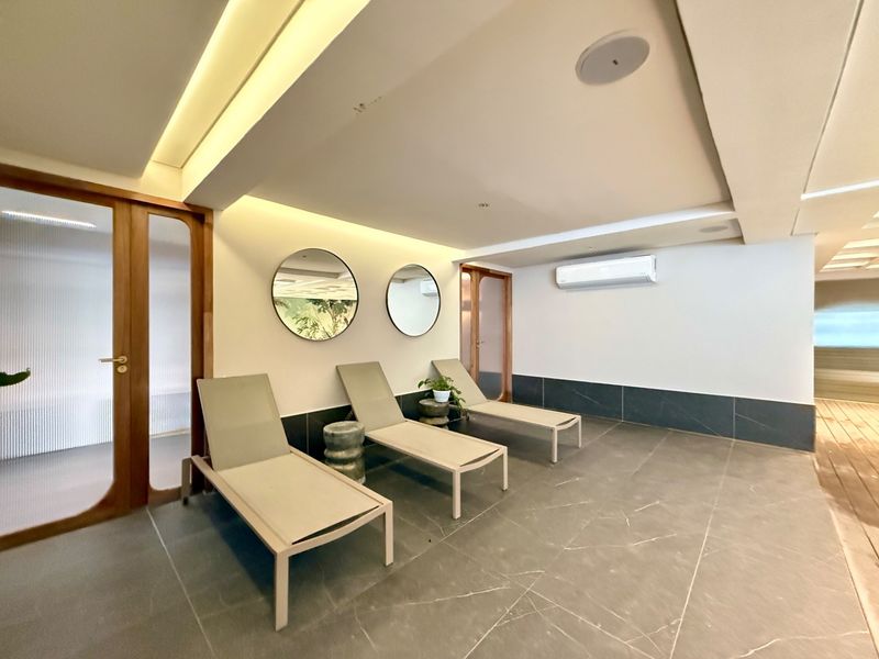 A modern, well-maintained relaxation area featuring tiled floors, recessed ambient lighting, integrated ceiling speakers, and a split-system air conditioner.