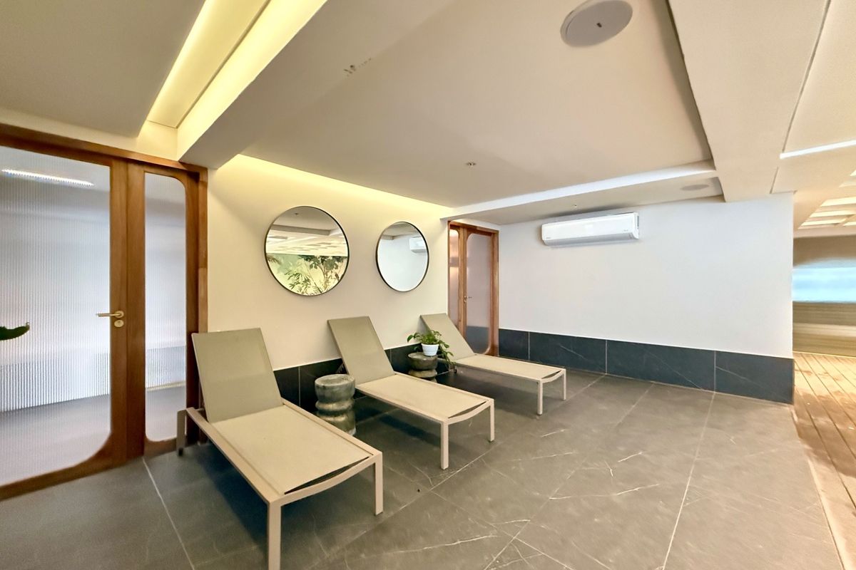 A modern, well-maintained relaxation area featuring tiled floors, recessed ambient lighting, integrated ceiling speakers, and a split-system air conditioner.