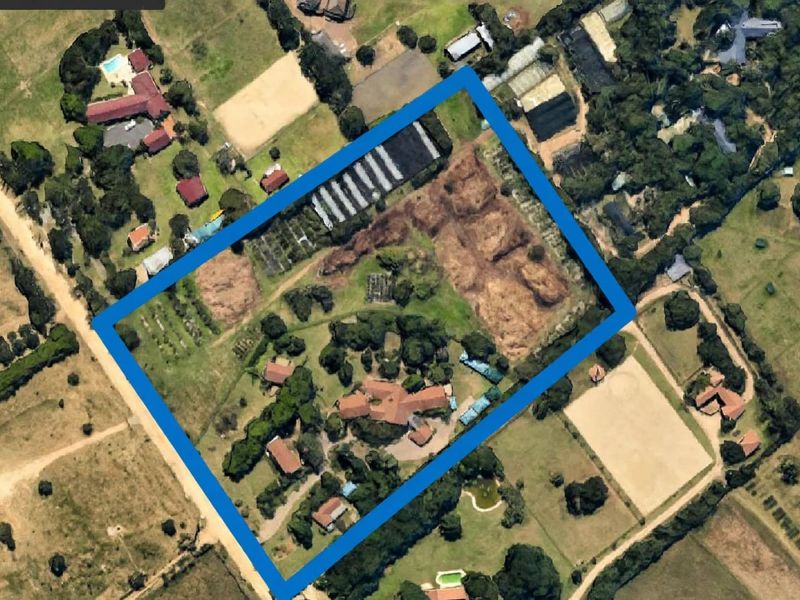 Aerial view of a large small holding property featuring a main residence, multiple outbuildings, and extensive grounds with cultivated areas and mature landscaping.