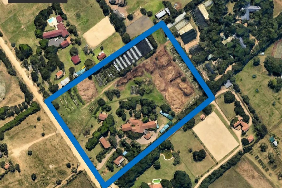 Aerial view of a large small holding property featuring a main residence, multiple outbuildings, and extensive grounds with cultivated areas and mature landscaping.