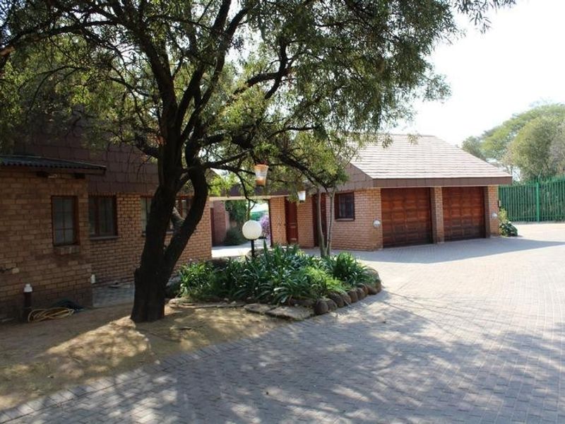 Front view of the property featuring a facebrick exterior, a paved driveway, and a double garage with wooden doors.