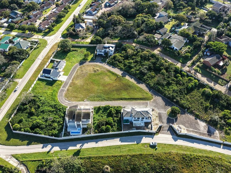 Aerial view of a vacant residential plot featuring a paved driveway, boundary walls, and gated access within an established neighborhood.