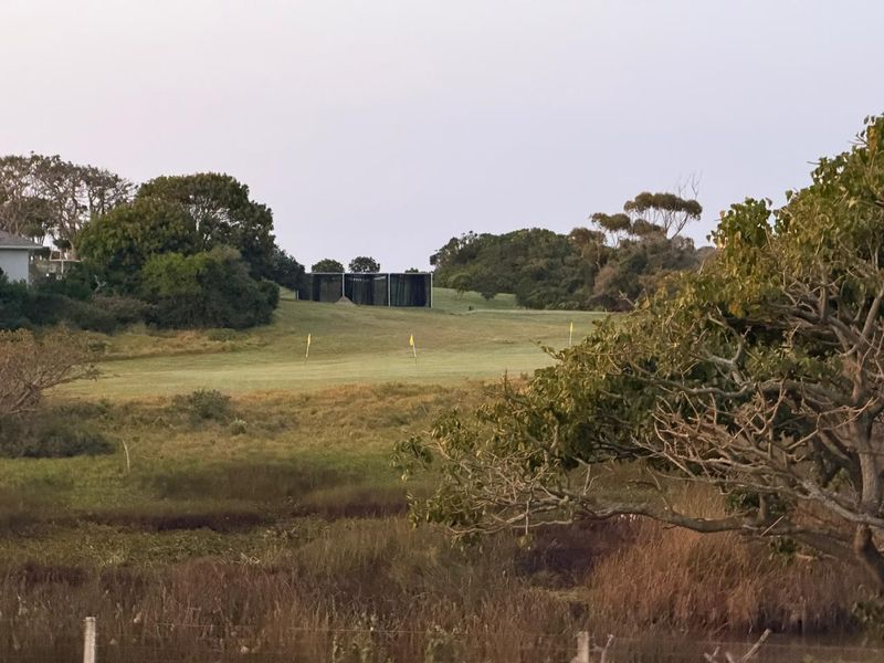 A scenic view overlooking a golf course fairway with surrounding natural vegetation and mature trees.