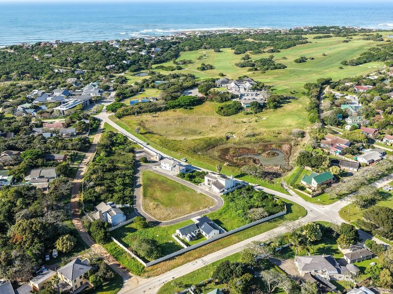 Aerial view of a vacant residential plot situated within a coastal estate, featuring established surrounding infrastructure and proximity to the golf course and ocean.