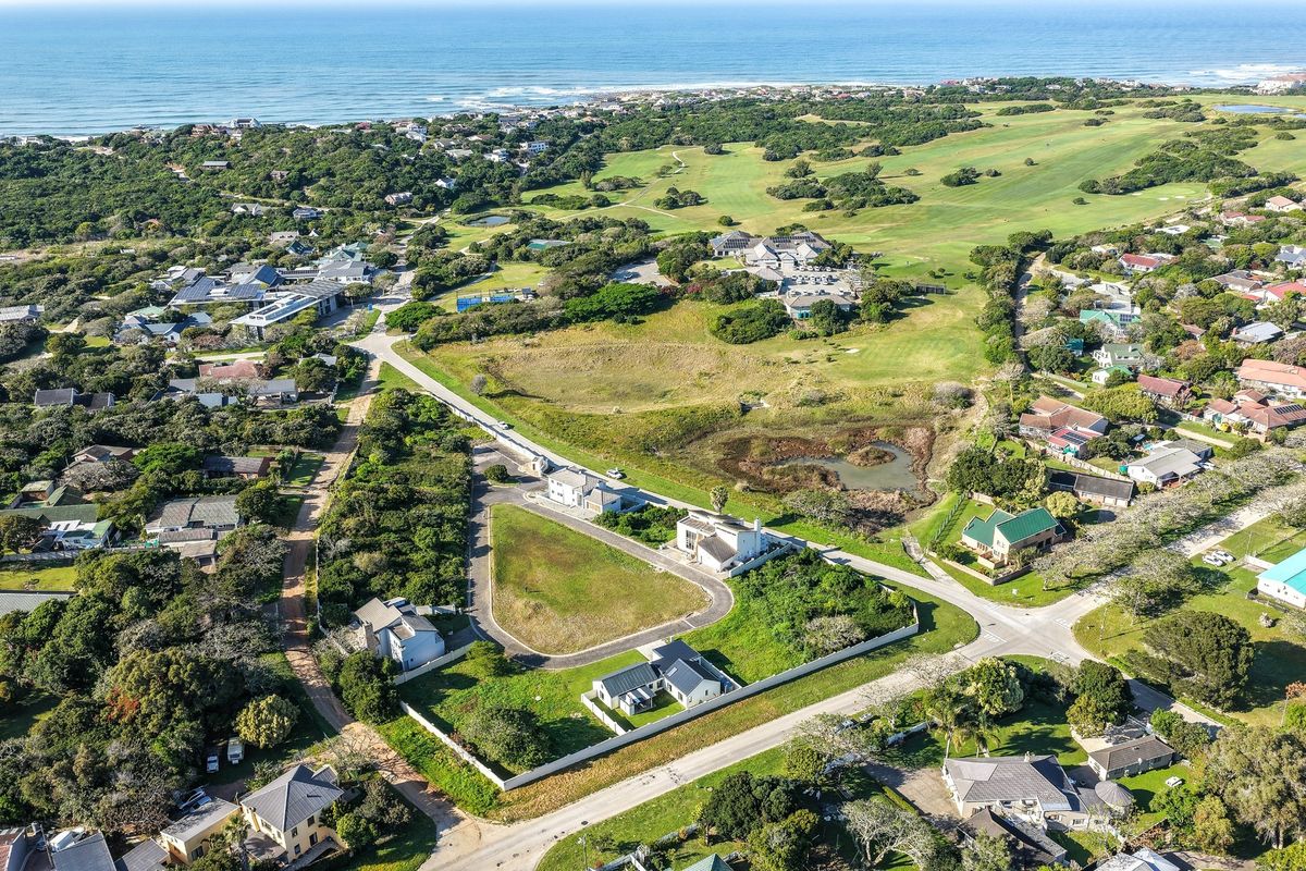 Aerial view of a vacant residential plot situated within a coastal estate, featuring established surrounding infrastructure and proximity to the golf course and ocean.