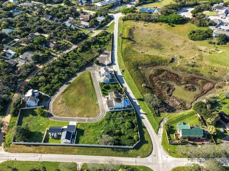 Aerial view of a residential vacant land plot situated within a developed estate, featuring established boundary walls and paved access.