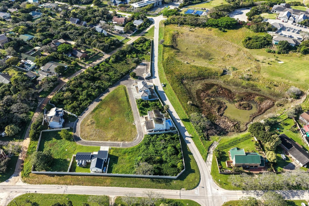 Aerial view of a residential vacant land plot situated within a developed estate, featuring established boundary walls and paved access.