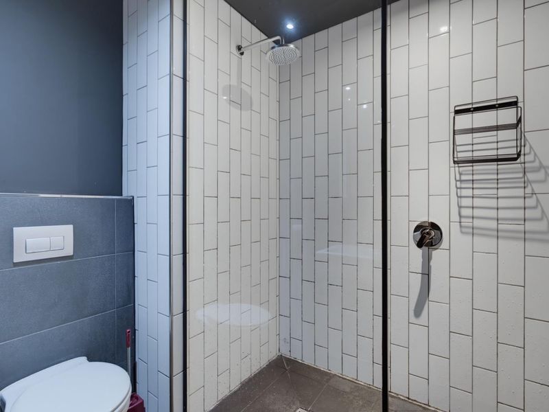 Modern bathroom featuring a walk-in shower with subway tiling, glass screen, and a wall-mounted toilet with contemporary finishes.
