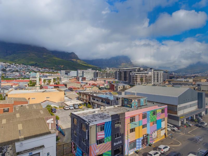 Elevated urban outlook featuring a panoramic cityscape view with mountain backdrop, captured from an apartment window.
