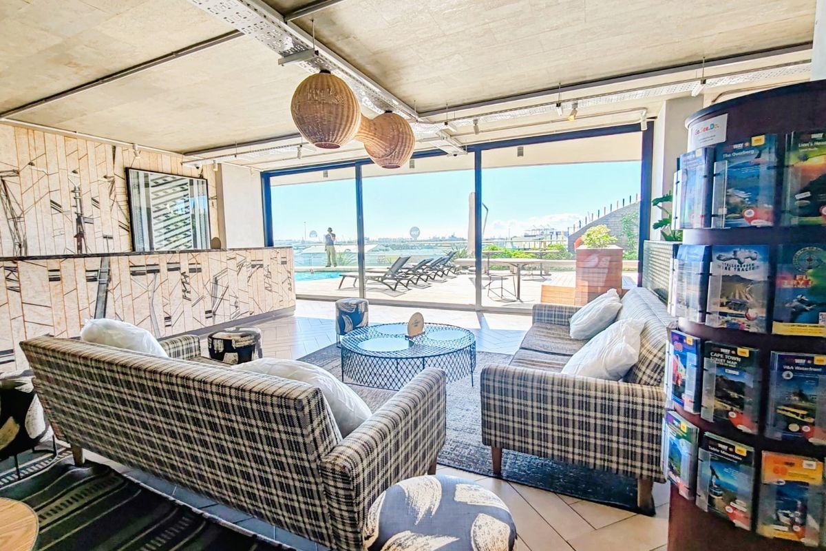 A modern living area featuring exposed concrete ceilings, large sliding glass doors providing natural light, and direct access to an outdoor pool deck.
