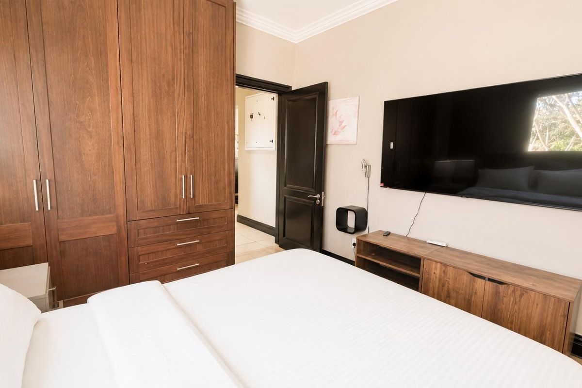 A well-maintained bedroom featuring extensive built-in wooden cabinetry, crown molding, and neutral wall finishes.