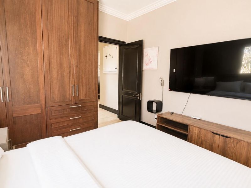 A well-maintained bedroom featuring extensive built-in wooden cabinetry, crown molding, and neutral wall finishes.