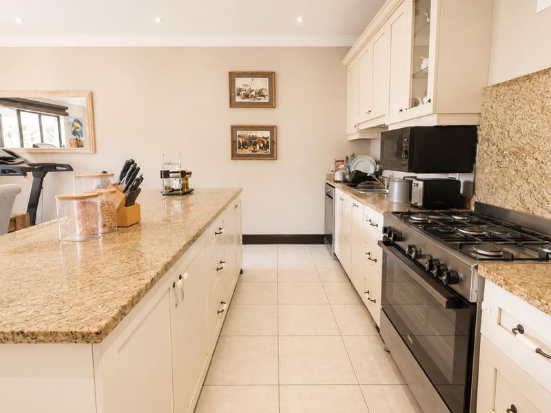Spacious kitchen featuring a large granite-topped island, ample cabinetry, and a professional-style gas stove with integrated oven and extractor fan.