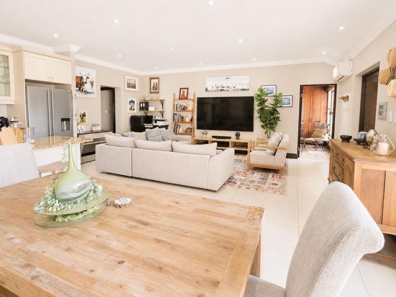 Spacious open-plan living area featuring a modern kitchen with granite countertops, tiled flooring, and recessed lighting, seamlessly flowing into the dining and lounge space.