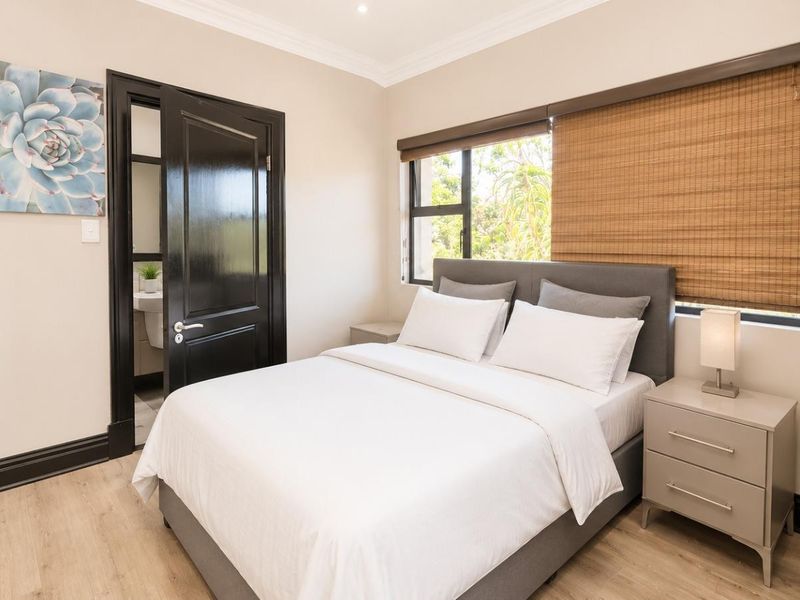 A well-maintained bedroom featuring laminate flooring, crown molding, built-in wardrobe, and an en-suite bathroom access.