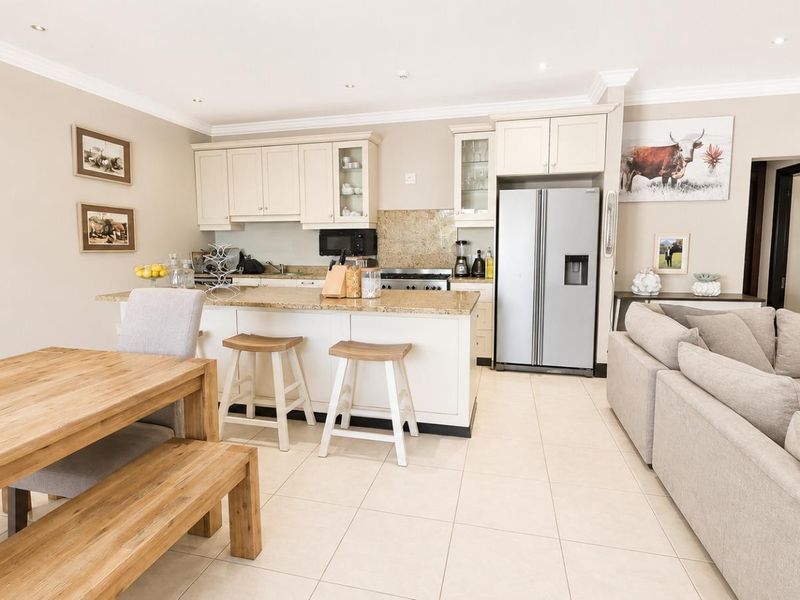 Spacious open-plan kitchen and living area featuring granite countertops, neutral cabinetry, tiled flooring, and recessed lighting, creating a bright and functional living space.