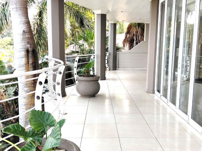 A spacious covered balcony featuring tiled flooring, modern metal balustrades, and large sliding glass doors providing seamless indoor-outdoor flow.