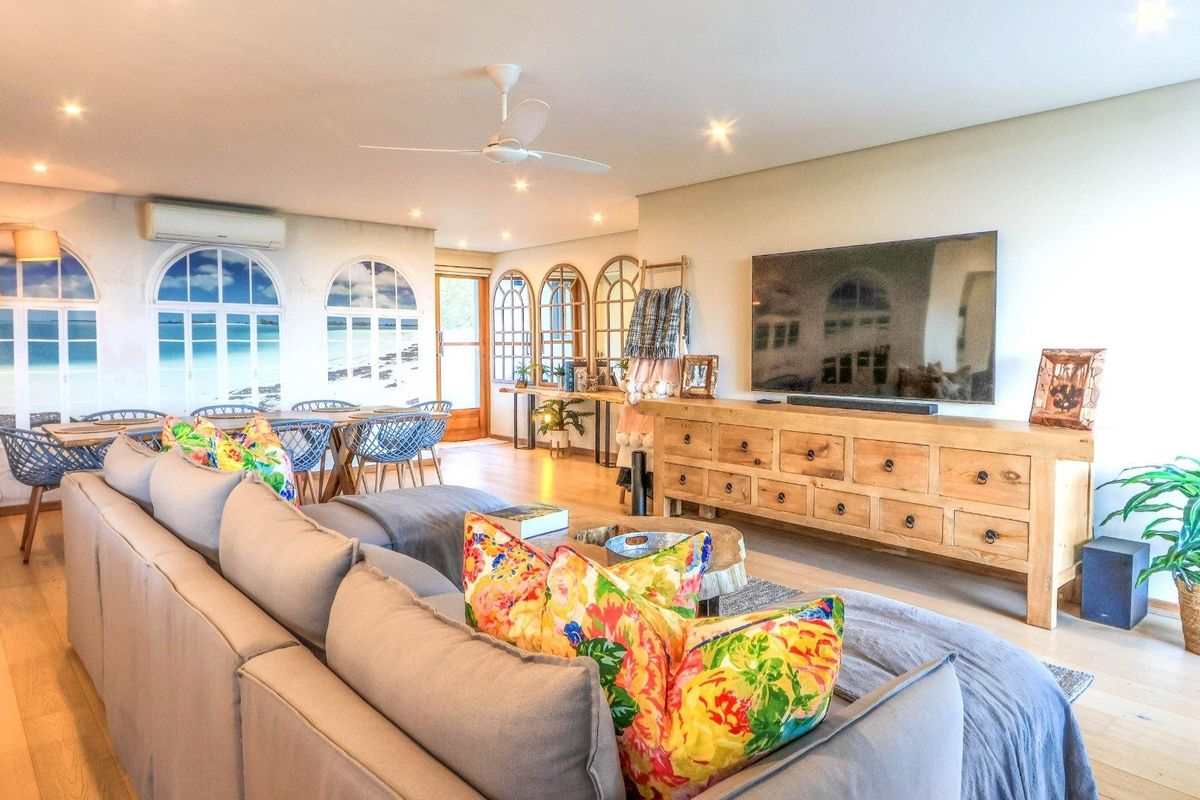 Spacious living area featuring timber flooring, recessed downlights, a ceiling fan, and decorative arched window features, creating a bright and inviting atmosphere.