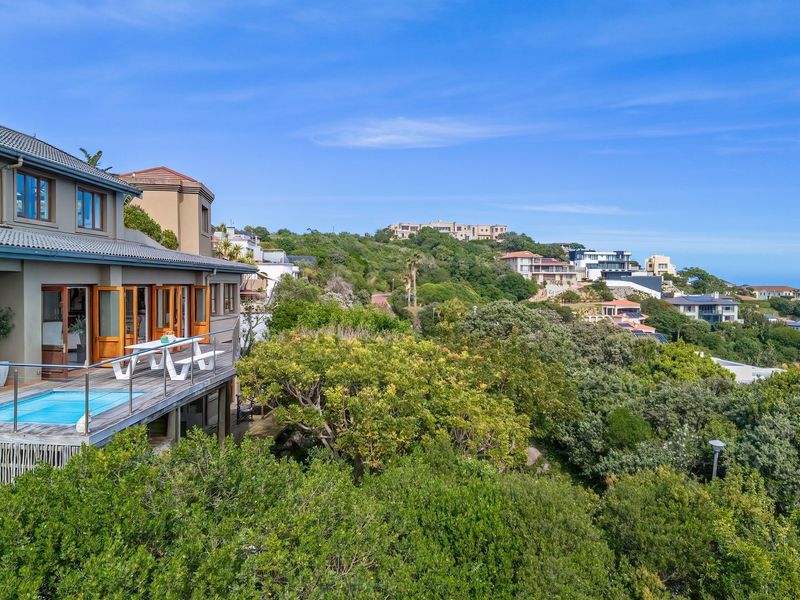 Rear elevation featuring a timber deck with a plunge pool, stainless steel balustrades, and expansive views over the surrounding landscape.