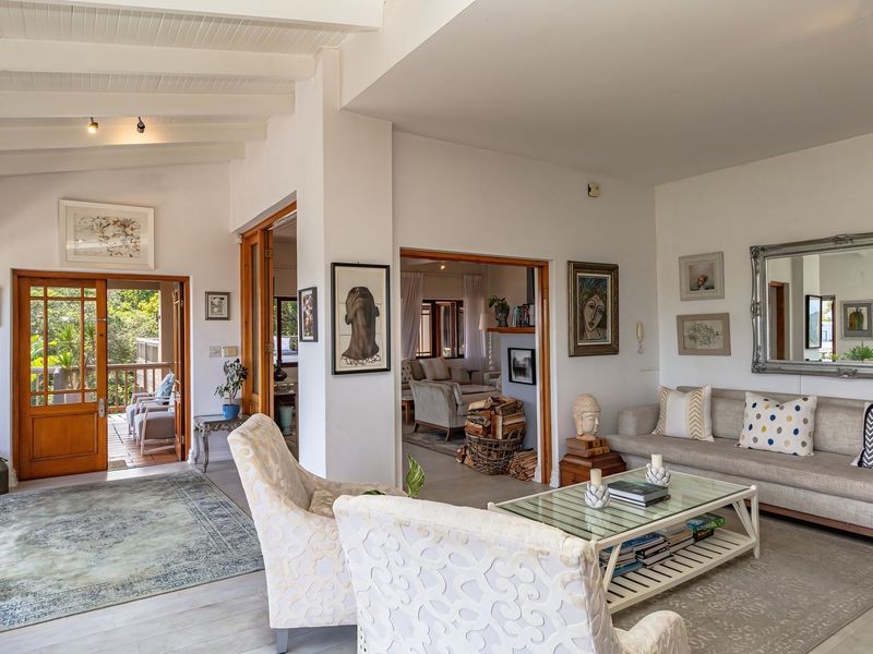Spacious living area featuring exposed timber ceiling beams, tiled flooring, and timber-framed glass doors leading to an outdoor patio space.