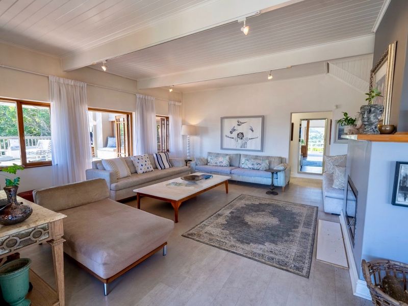 Spacious living room featuring a fireplace, exposed beam ceiling, and large sliding glass doors that provide ample natural light and access to the patio.