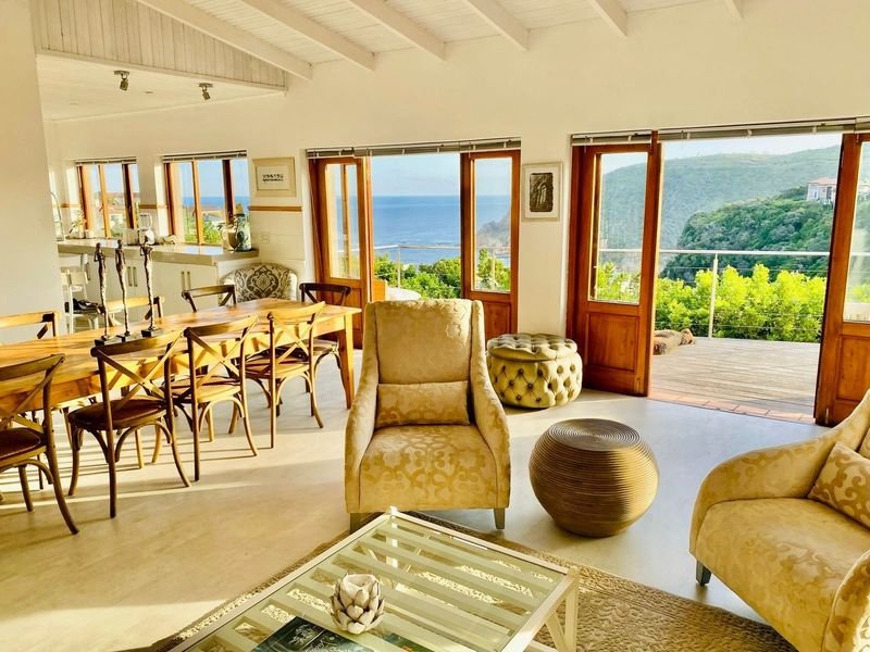 Spacious open-plan living and dining area featuring exposed beam ceilings, timber-framed doors, and expansive ocean views.
