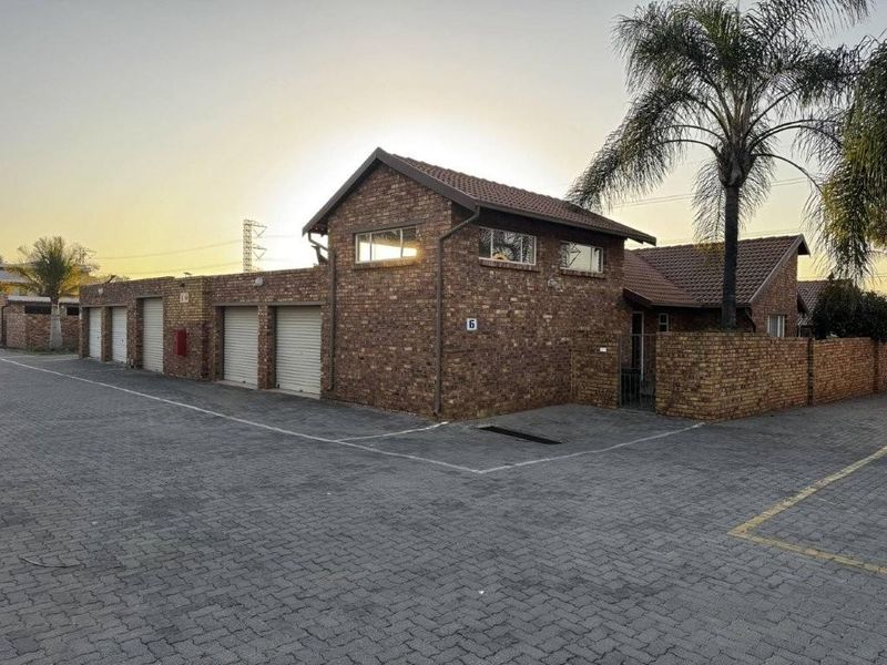 Front exterior view of a face-brick townhouse featuring multiple garage doors, a tiled roof, and a paved driveway area.