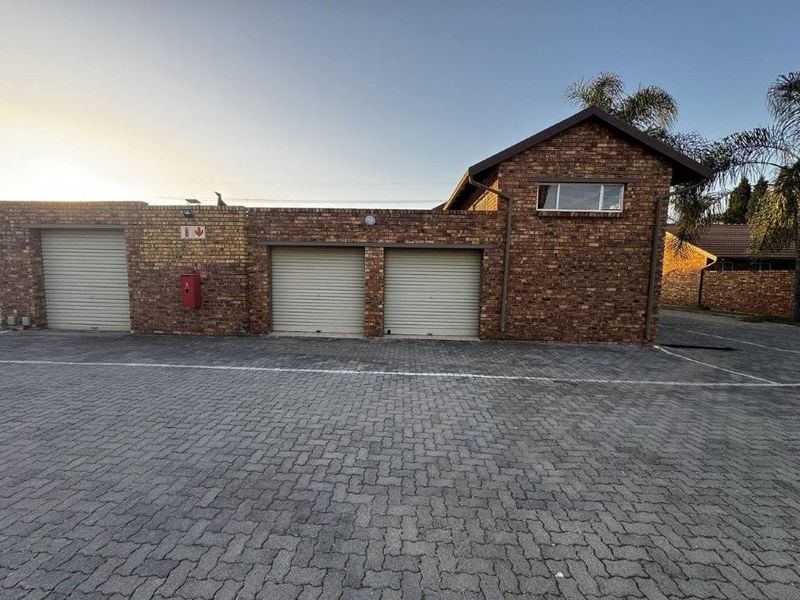 Exterior view of a townhouse complex featuring multiple roller shutter garage doors and a paved driveway area.