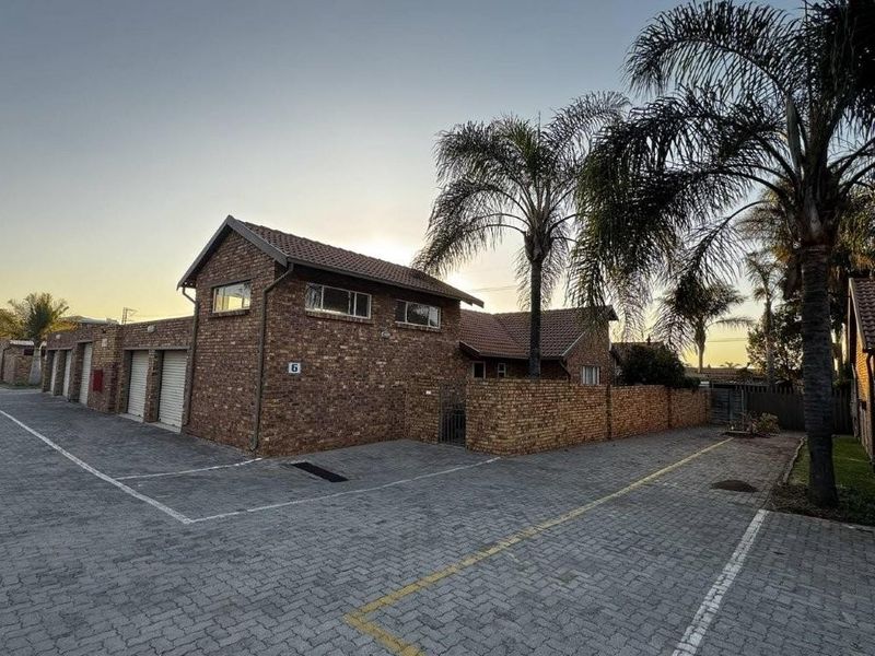 Front exterior view of a face brick townhouse featuring a tiled roof, paved driveway, and integrated garage access.