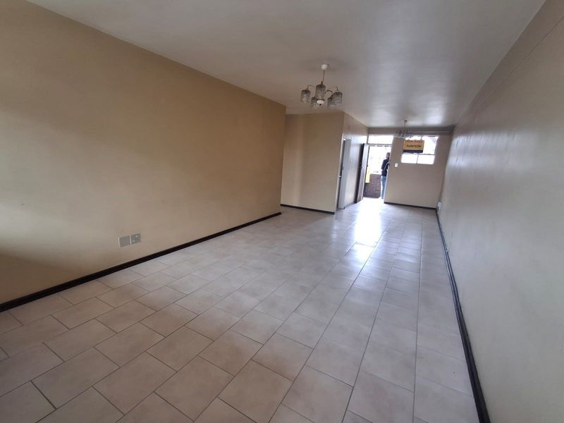 An empty, open-plan living area featuring neutral tiled flooring and a simple ceiling light fixture, ready for personalization.