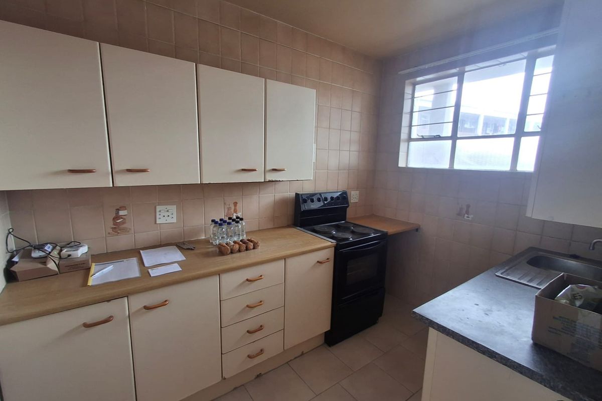 A functional kitchen featuring built-in cabinetry, laminate countertops, an electric stove, and tiled backsplash, offering a practical layout for daily use.