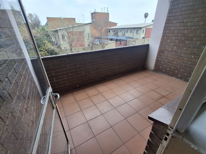 A private balcony featuring tiled flooring and a brick balustrade, offering an outdoor space accessible via a sliding glass door.