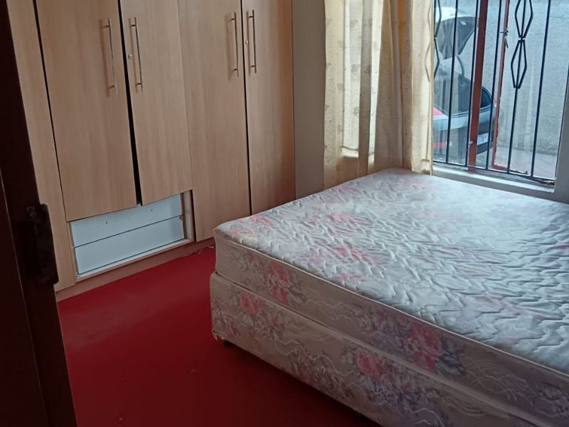 Bedroom featuring built-in wooden wardrobes, red carpeting, and security bars on the window.