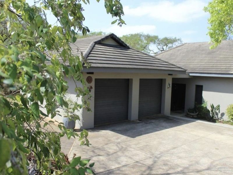 Front view of the property featuring a double garage with a concrete driveway and a tiled roof structure.