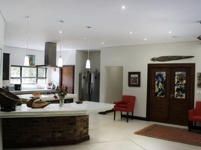 Spacious open-plan kitchen and living area featuring a brick-base island, modern cabinetry, recessed lighting, and elegant double doors with stained glass accents.