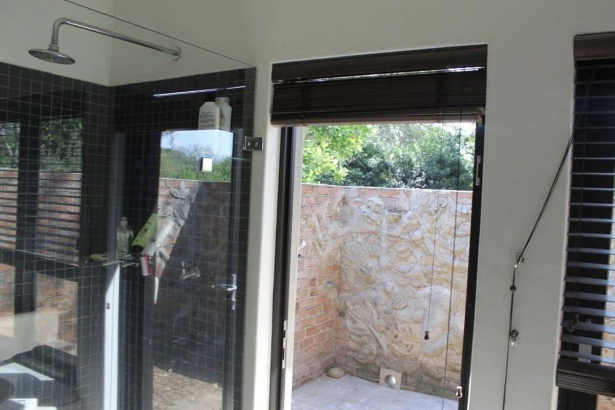 Modern bathroom featuring a walk-in shower with mosaic tiling and direct access to a private outdoor courtyard area.
