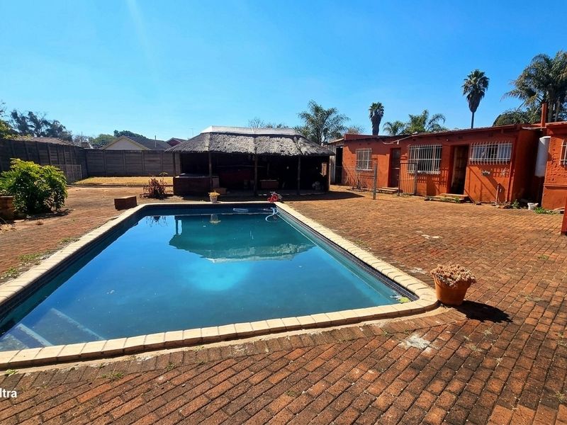 Outdoor pool area featuring a swimming pool, brick-paved patio, and a thatched lapa, providing a functional space for outdoor entertainment.