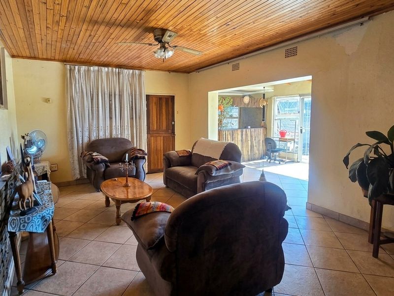 Spacious living room featuring a timber ceiling, tiled flooring, and a stone fireplace, with direct access to an adjoining patio area.
