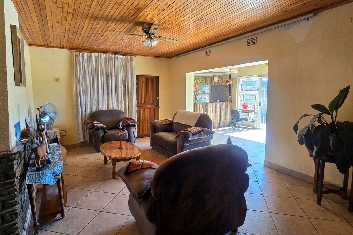 Spacious living room featuring a timber ceiling, tiled flooring, and a stone fireplace, with direct access to an adjoining patio area.